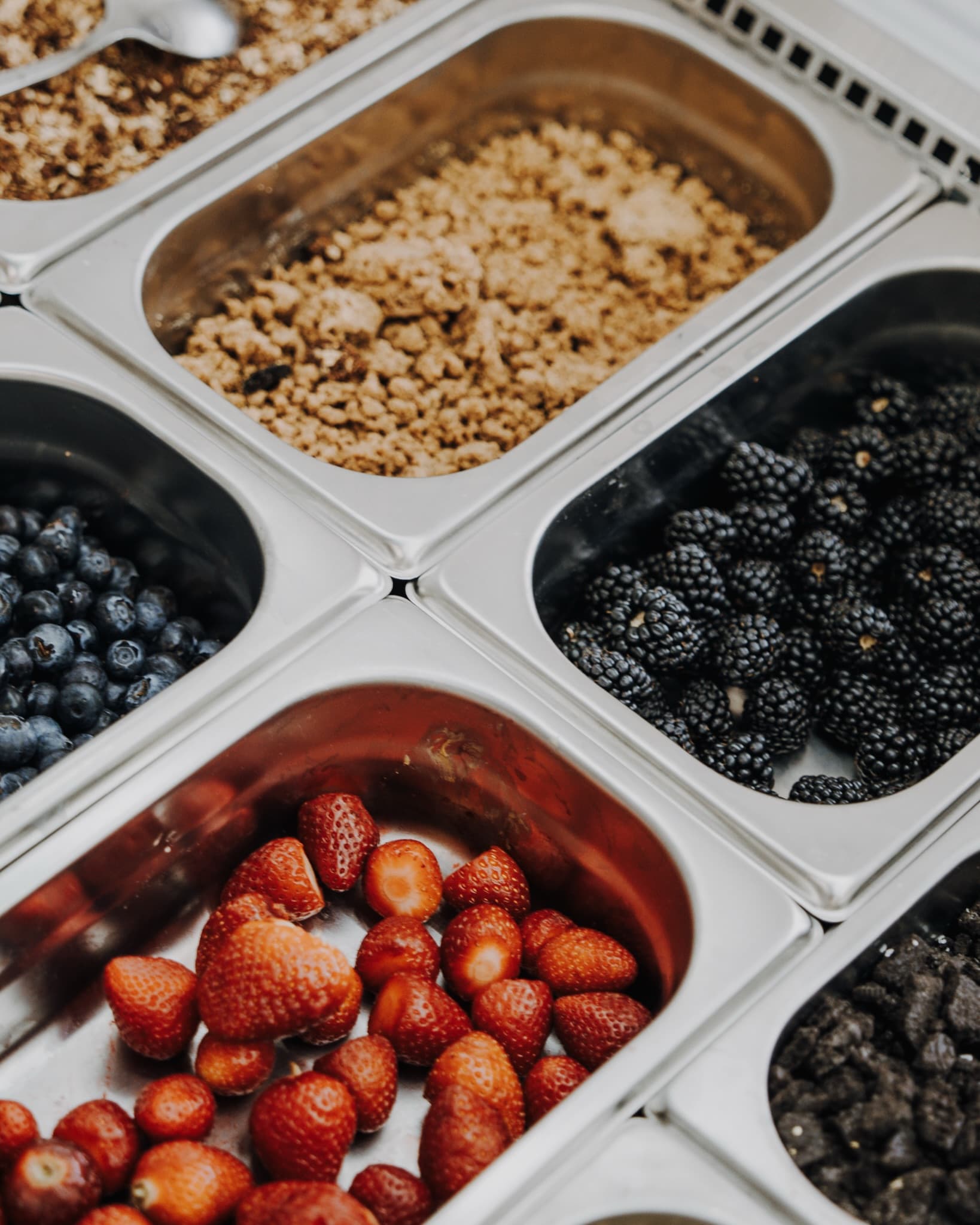 Behälter mit Erdbeeren, Heidelbeeren, Brombeeren und Granola an der Topping-Bar